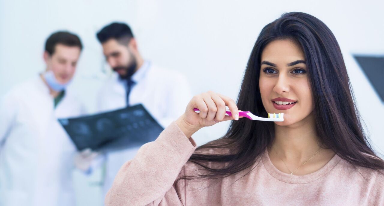Rosenthal Dark Haired Woman Brushing Teeth Alongside Dentists