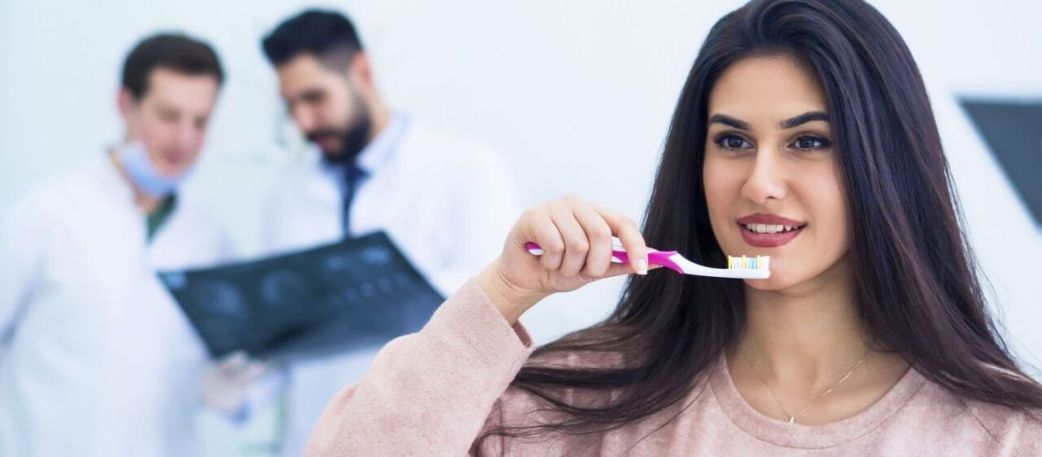 Rosenthal Dark Haired Woman Brushing Teeth Alongside Dentists
